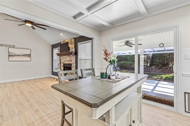 dining space with vaulted ceiling with beams, light wood-type flooring, a fireplace, and visible vents