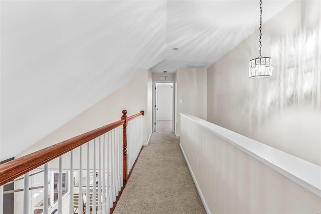 hallway featuring lofted ceiling, baseboards, an upstairs landing, and light colored carpet