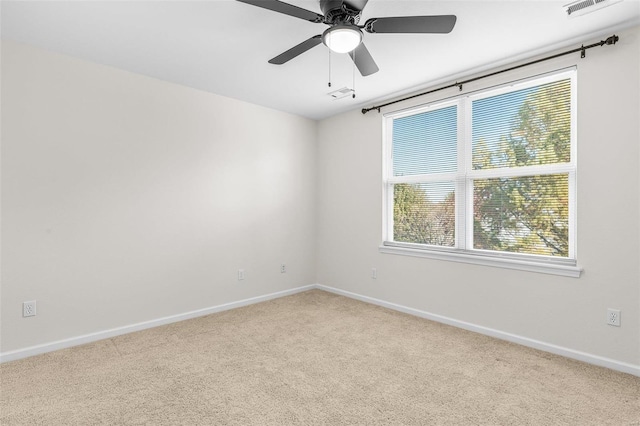 empty room with visible vents, baseboards, a ceiling fan, and light colored carpet