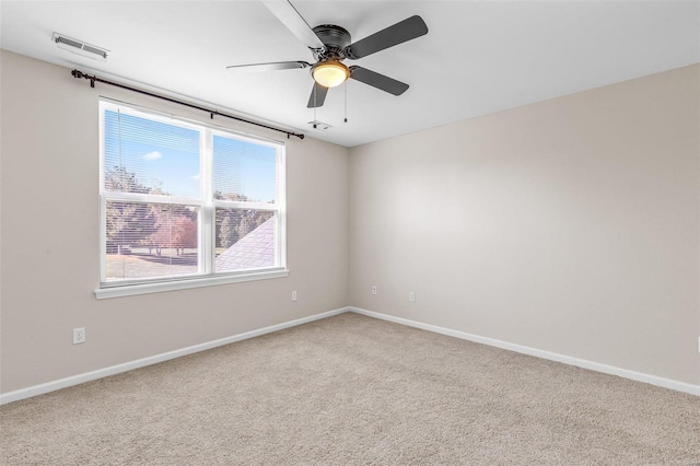 empty room with ceiling fan, carpet floors, visible vents, and baseboards