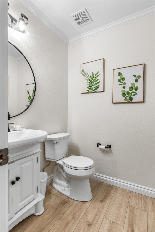 half bathroom featuring ornamental molding, visible vents, toilet, and wood finished floors