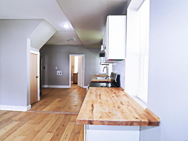 kitchen with backsplash, butcher block counters, light hardwood / wood-style floors, white cabinetry, and sink