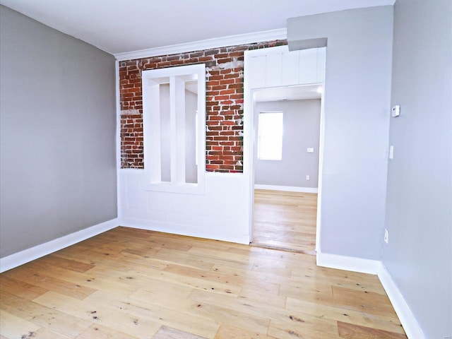 spare room featuring light wood-type flooring and brick wall