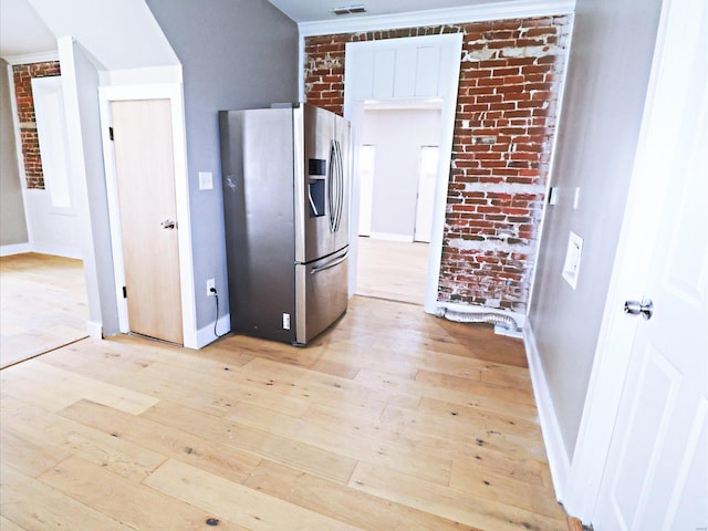 kitchen featuring light wood-type flooring, stainless steel refrigerator with ice dispenser, brick wall, and ornamental molding