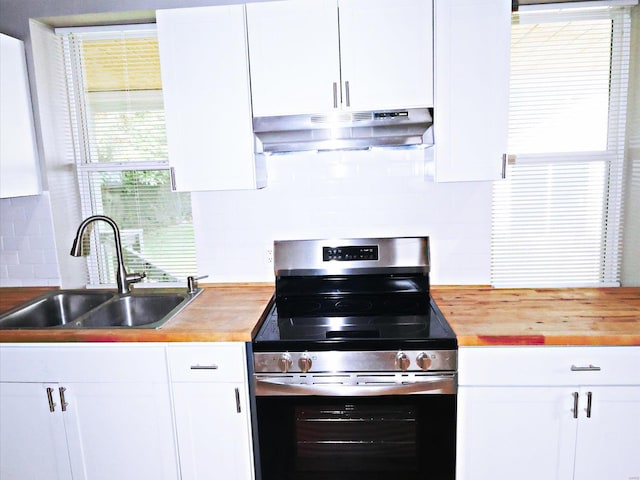 kitchen featuring butcher block countertops, stainless steel range with electric cooktop, tasteful backsplash, white cabinetry, and sink