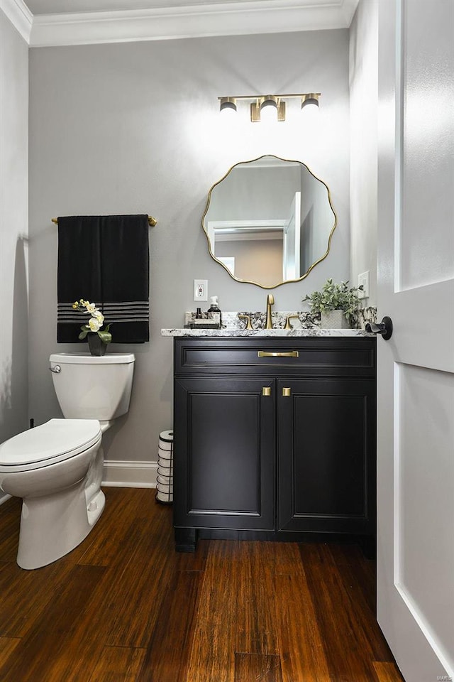 bathroom with crown molding, hardwood / wood-style flooring, vanity, and toilet