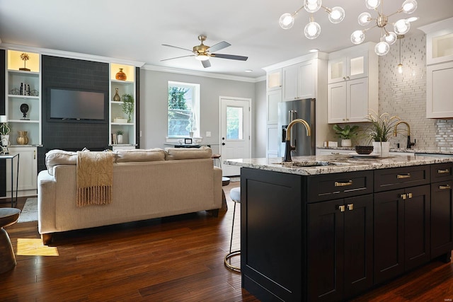 kitchen with crown molding, pendant lighting, dark hardwood / wood-style floors, white cabinets, and an island with sink