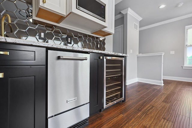 kitchen featuring white cabinetry, dark wood-type flooring, light stone countertops, stainless steel appliances, and beverage cooler