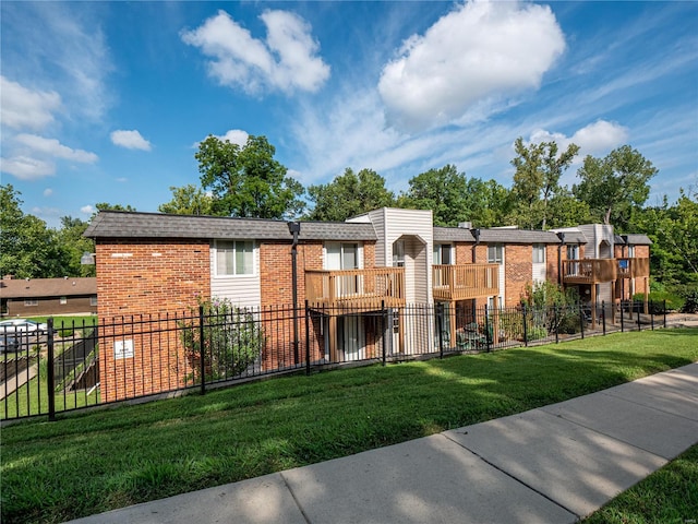 exterior space featuring fence, a residential view, roof with shingles, a front yard, and brick siding