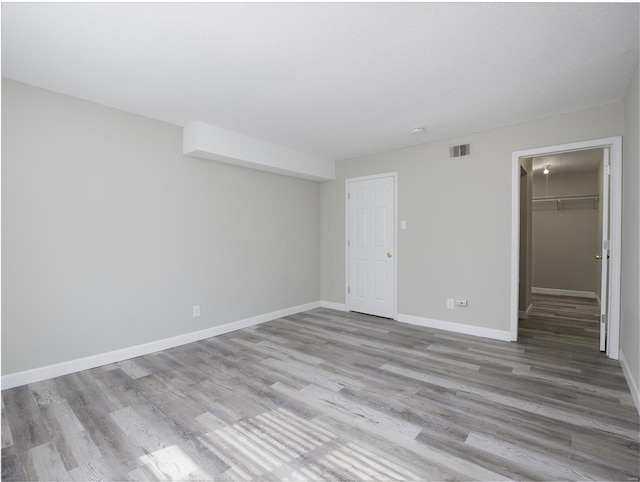 unfurnished bedroom with visible vents, wood finished floors, a closet, baseboards, and a spacious closet