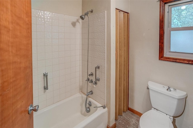 bathroom featuring tiled shower / bath combo and toilet