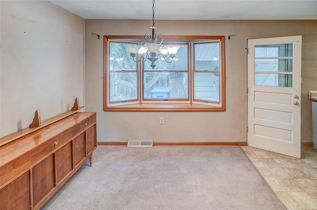 unfurnished dining area with a chandelier and light carpet