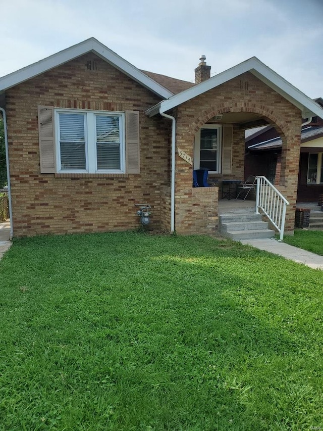 ranch-style house with a front yard, brick siding, and a chimney