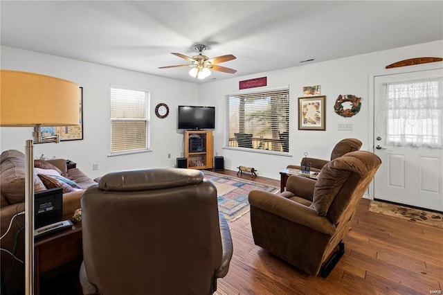 living room featuring wood finished floors, visible vents, and a ceiling fan