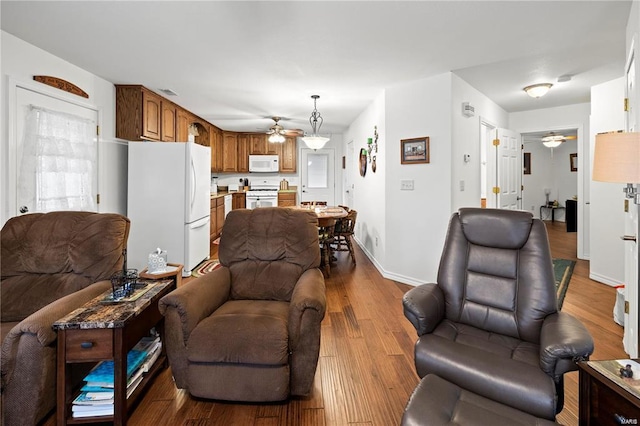 living room with a ceiling fan, baseboards, and wood finished floors