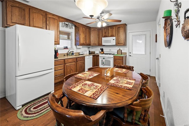 kitchen featuring white appliances, wood finished floors, a sink, light countertops, and brown cabinetry