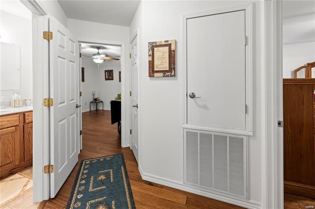 corridor featuring light wood-style floors, visible vents, and baseboards