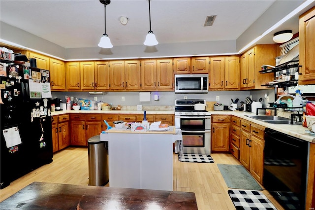 kitchen with light hardwood / wood-style flooring, a kitchen island, hanging light fixtures, sink, and black appliances