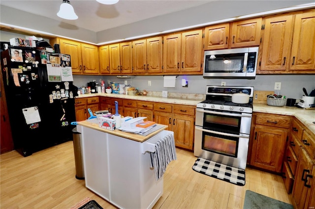 kitchen featuring light hardwood / wood-style flooring, range with two ovens, and black fridge