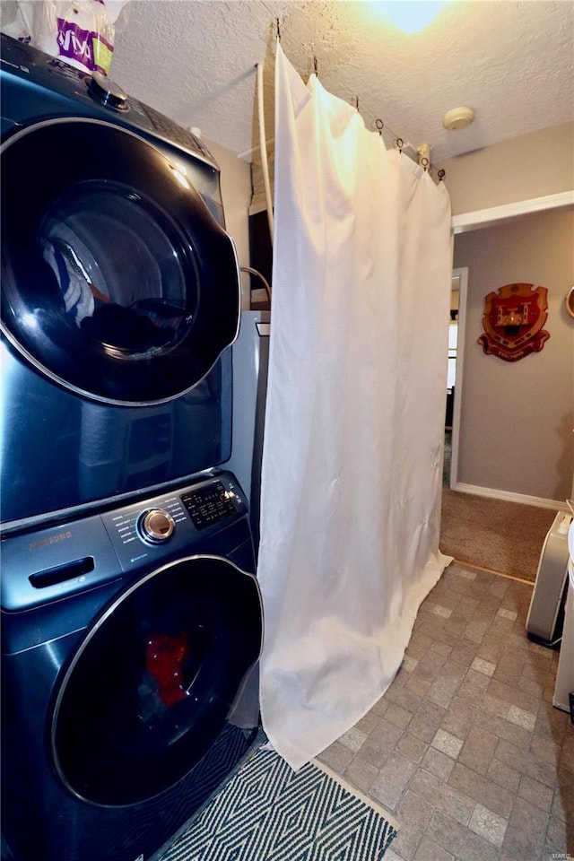 clothes washing area with a textured ceiling, stacked washing maching and dryer, and light tile patterned floors