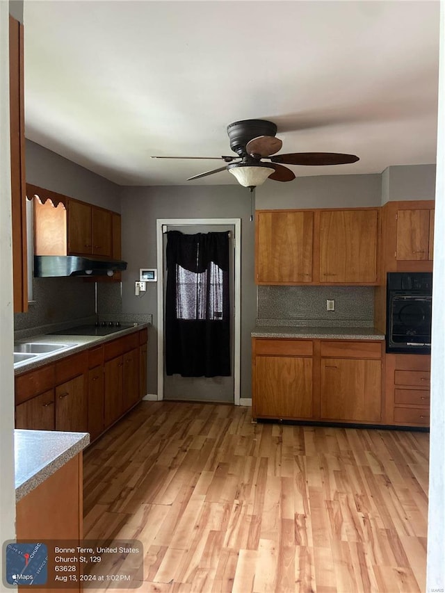 kitchen featuring ceiling fan, tasteful backsplash, light hardwood / wood-style floors, and oven