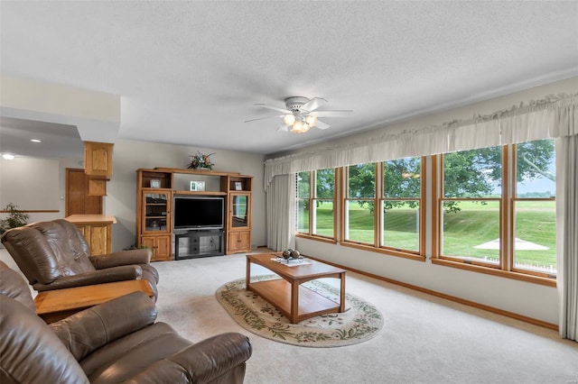 living room with ceiling fan, a textured ceiling, and light carpet