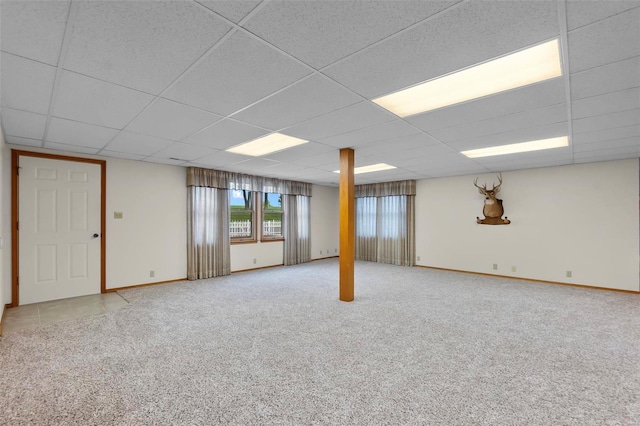 basement with a paneled ceiling and light colored carpet