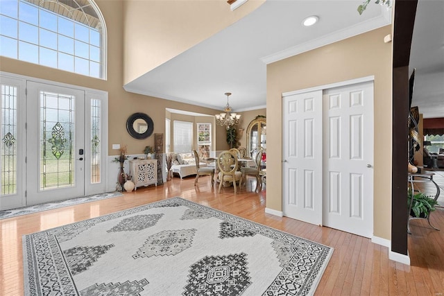 entrance foyer with ornamental molding, light hardwood / wood-style flooring, and a notable chandelier