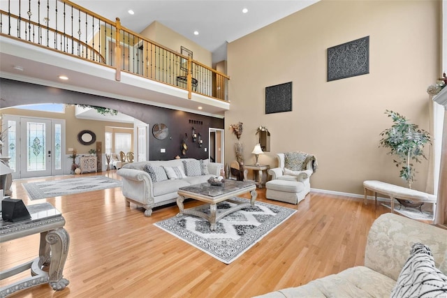 living room with a towering ceiling and light hardwood / wood-style floors