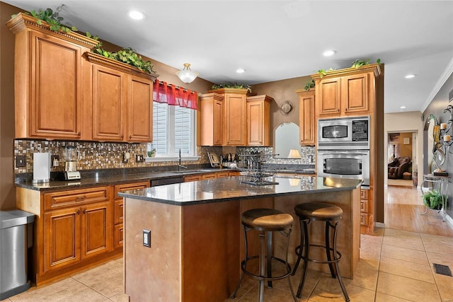 kitchen with crown molding, light wood-type flooring, stainless steel appliances, a breakfast bar area, and a kitchen island