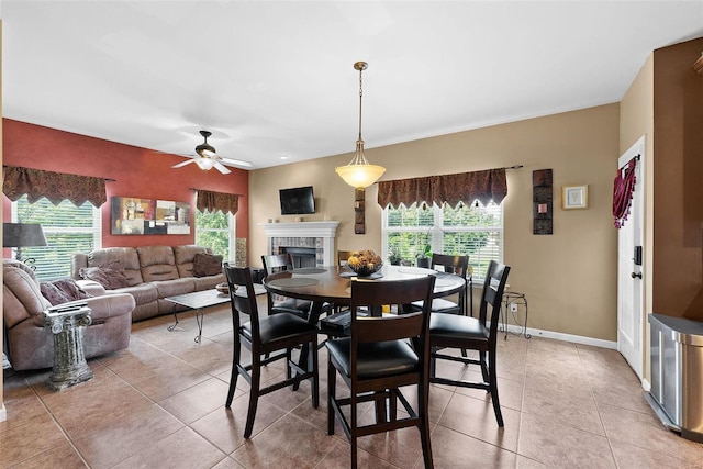 tiled dining space with ceiling fan, a tile fireplace, and plenty of natural light