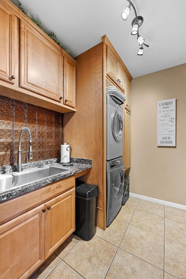 interior space featuring dark stone countertops, backsplash, sink, light tile patterned flooring, and stacked washer / drying machine