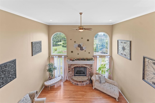 living room featuring light wood-type flooring, ceiling fan, plenty of natural light, and a brick fireplace