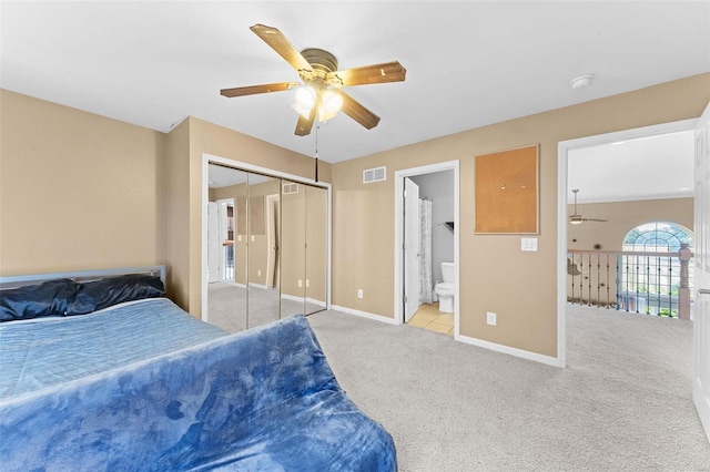 bedroom with a closet, ceiling fan, light carpet, and ensuite bathroom