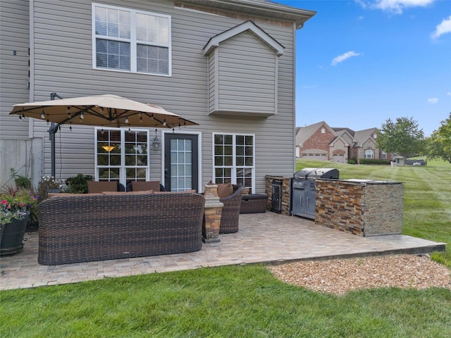 rear view of property featuring outdoor lounge area, a lawn, an outdoor kitchen, and a patio area