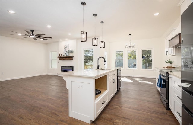 kitchen featuring white cabinets, an island with sink, hanging light fixtures, sink, and stainless steel electric stove