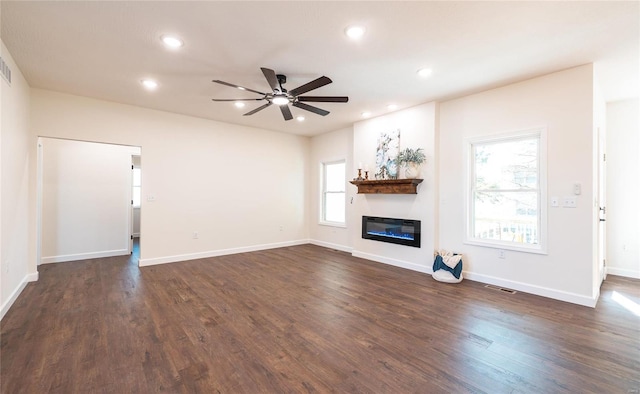 unfurnished living room featuring a healthy amount of sunlight, ceiling fan, and dark hardwood / wood-style flooring