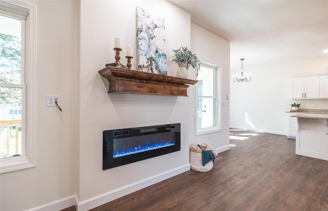 unfurnished living room with a wealth of natural light, an inviting chandelier, and dark hardwood / wood-style floors