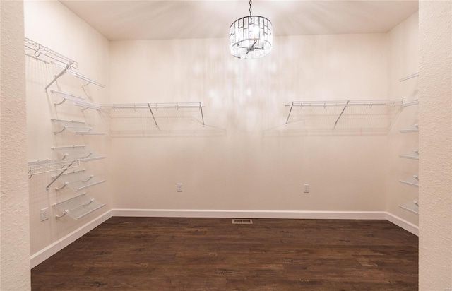 spacious closet with a notable chandelier and dark hardwood / wood-style flooring