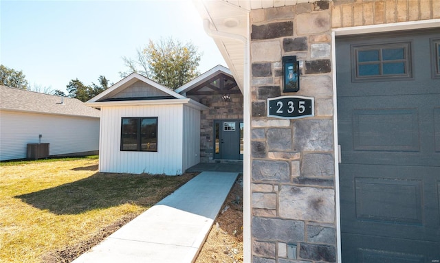 property entrance with cooling unit and a lawn