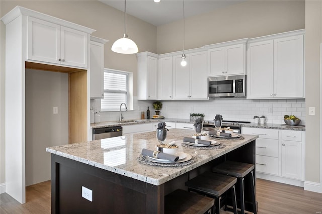 kitchen featuring backsplash, stainless steel appliances, a center island, and light hardwood / wood-style flooring