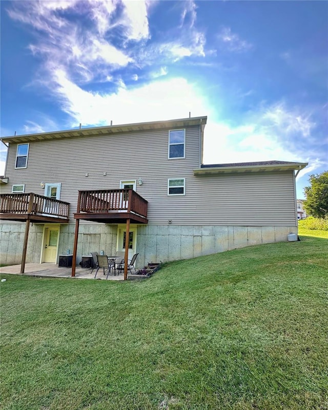 back of property with a wooden deck, a patio area, and a lawn