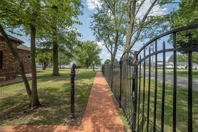 exterior space with a gate, fence, and a lawn