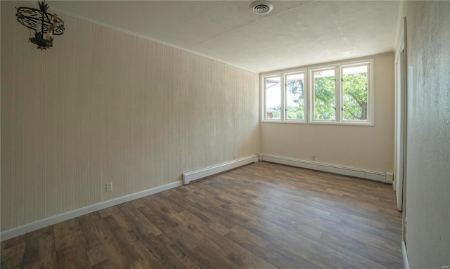 empty room featuring a baseboard radiator, wood finished floors, visible vents, and baseboards