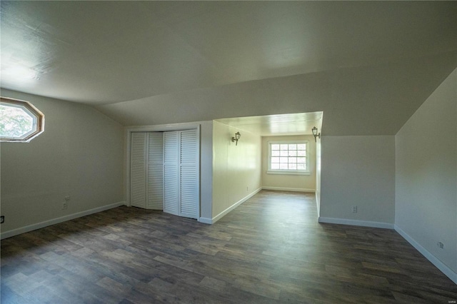 additional living space featuring lofted ceiling, dark wood-type flooring, and baseboards