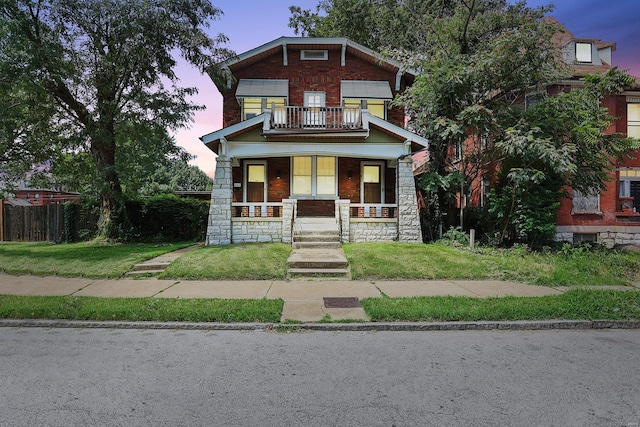 craftsman-style house featuring a balcony, covered porch, and a lawn