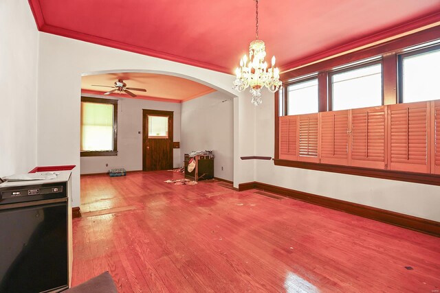 spare room with wood-type flooring, ceiling fan with notable chandelier, ornamental molding, and plenty of natural light