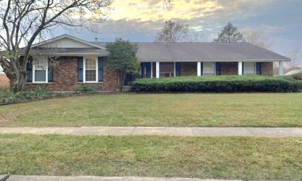 single story home with brick siding and a front yard