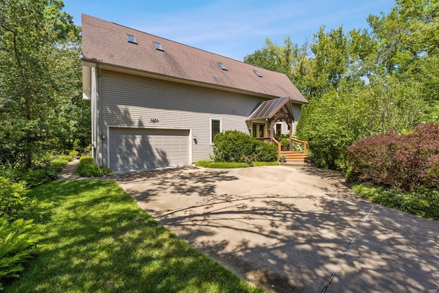 view of front facade with a garage, a front yard, concrete driveway, and a shingled roof