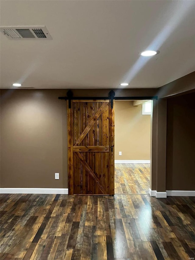 basement with hardwood / wood-style flooring and a barn door